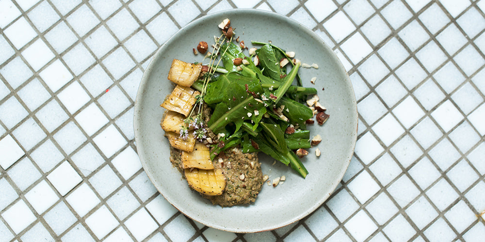 plate with Scalloped Oyster Mushrooms with Miso-Pea Purée and Dandelion Green Salad against a tiled background. This dish is gluten-free and vegan.